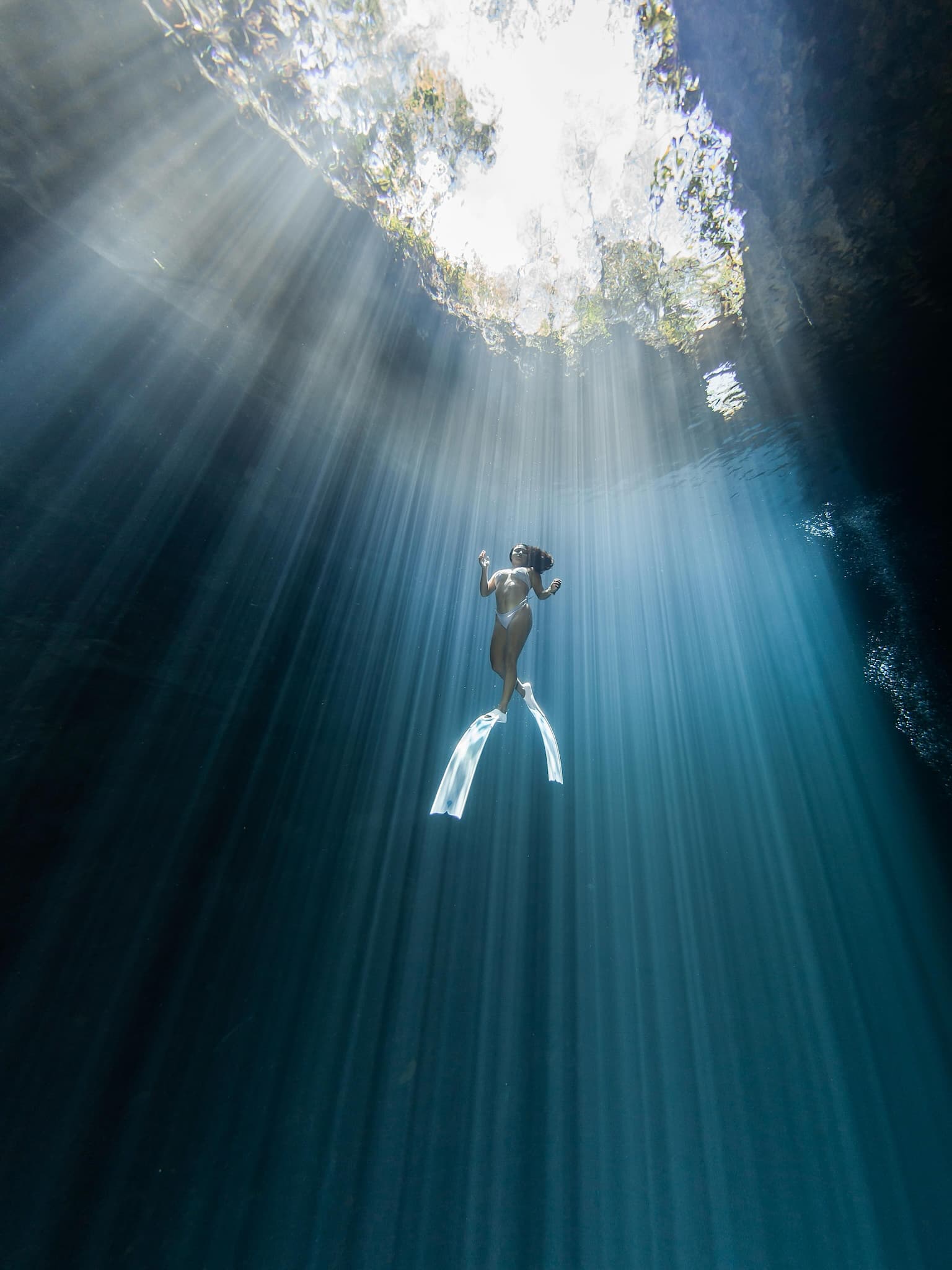 women diver in crystal-clear turquoise cave water inside Cenote Dos Ojos
