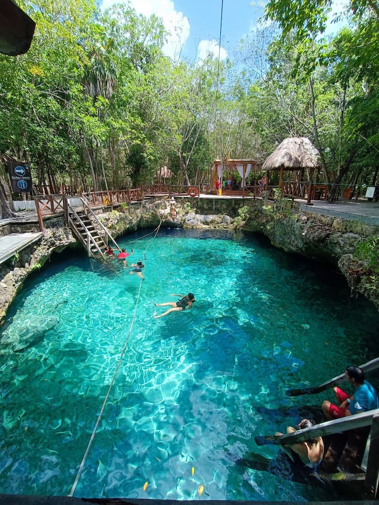 Travelers entering the clear turquoise water at Cenote Zacil-Ha