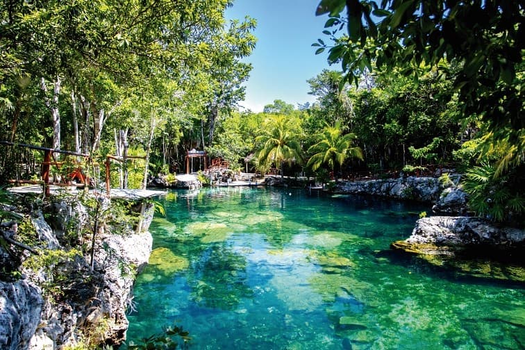 Aerial view of Cenote Zacil-Ha surrounded by jungle cabins